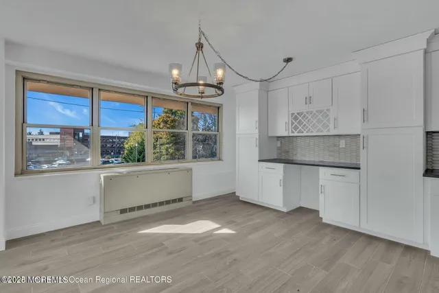 a kitchen with granite countertop a stove a sink and white cabinets with wooden floor