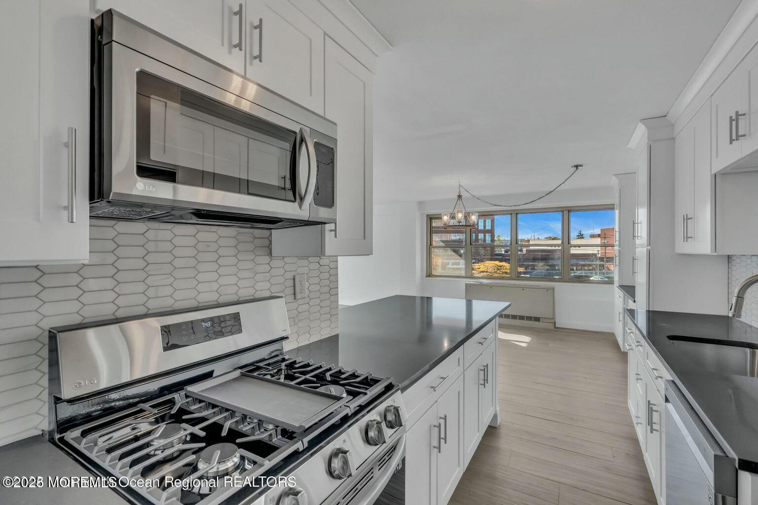 28 Riverside Avenue, Unit 1G Red Bank, NJ 07701 - Photo 5 of 25 a kitchen with stainless steel appliances a stove a microwave and cabinets