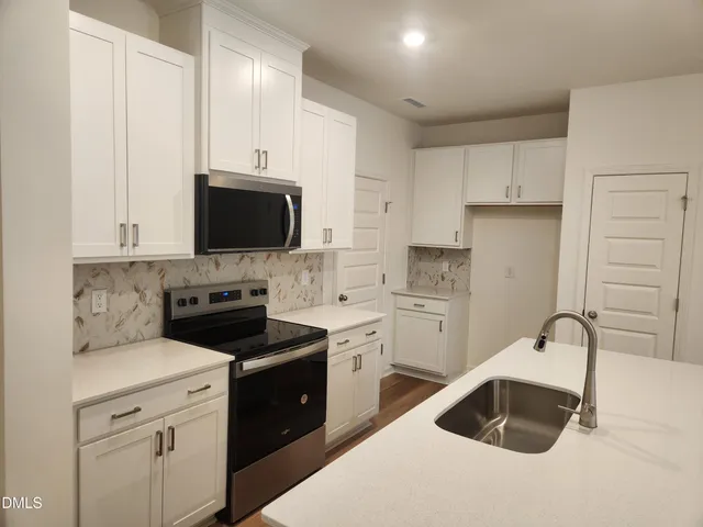 a kitchen with a sink stove and white cabinets