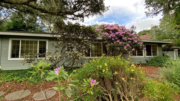 a front view of a house with a yard and a fountain