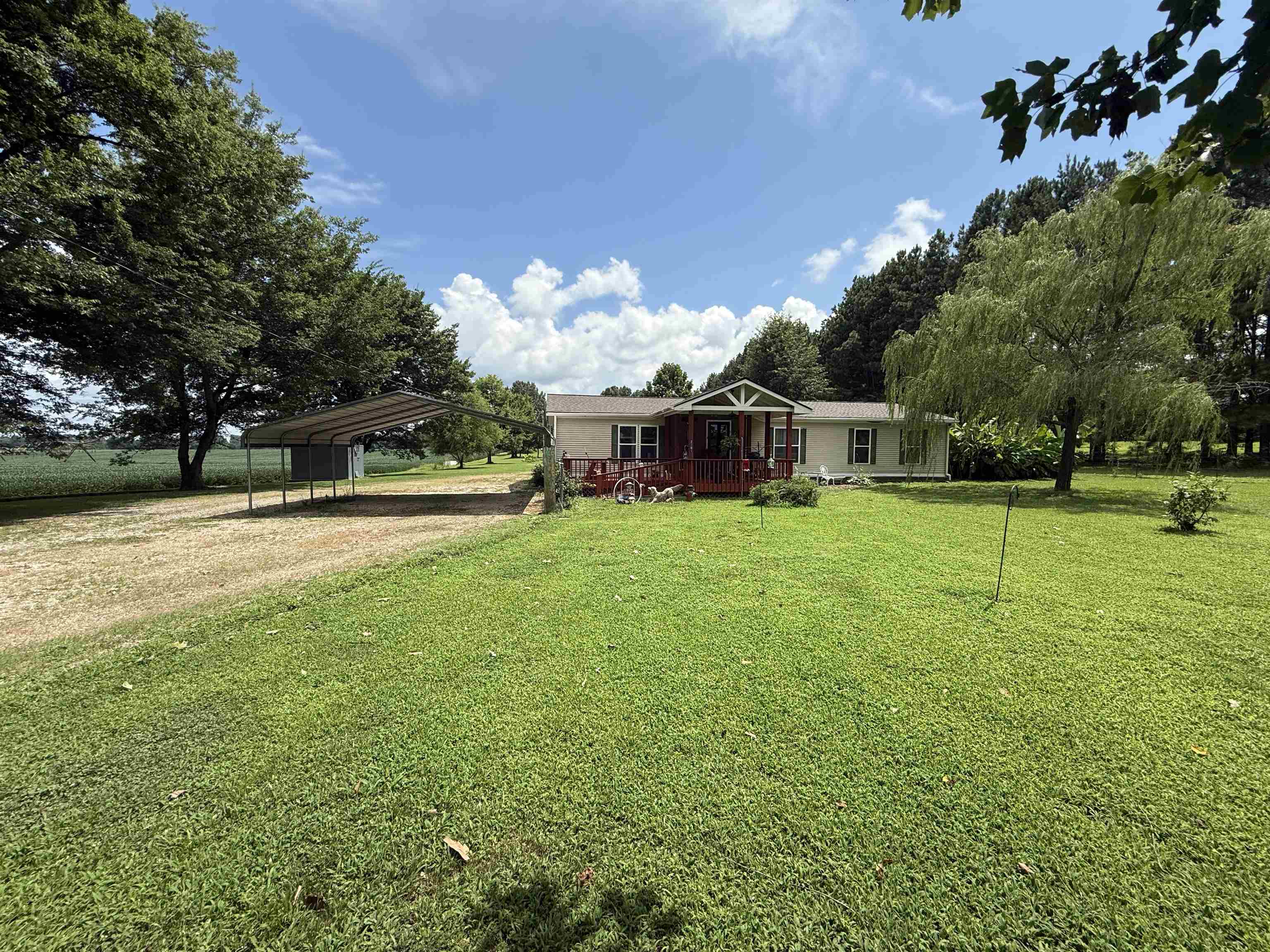 2201 Robert Johnson Road Covington, TN 38019 - Photo 1 of 25 Single-story home featuring a covered front porch with a gable roof, light-colored siding, and a metal carport