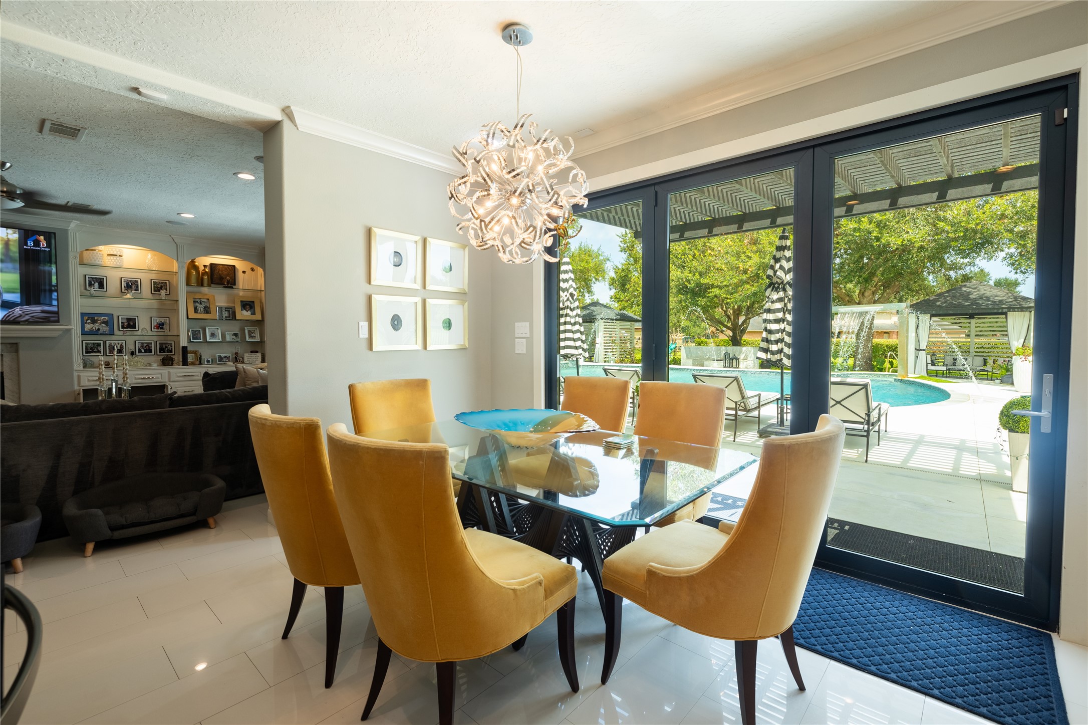 4002 Silver Ridge Boulevard Missouri City, TX 77459 - Photo 15 of 50 This is a bright and modern Breakfast area with stylish velvet chairs and a glass table, featuring an elegant light fixture. Large sliding glass doors provide a view and access to an inviting outdoor pool and patio space, perfect for entertaining and relaxing.