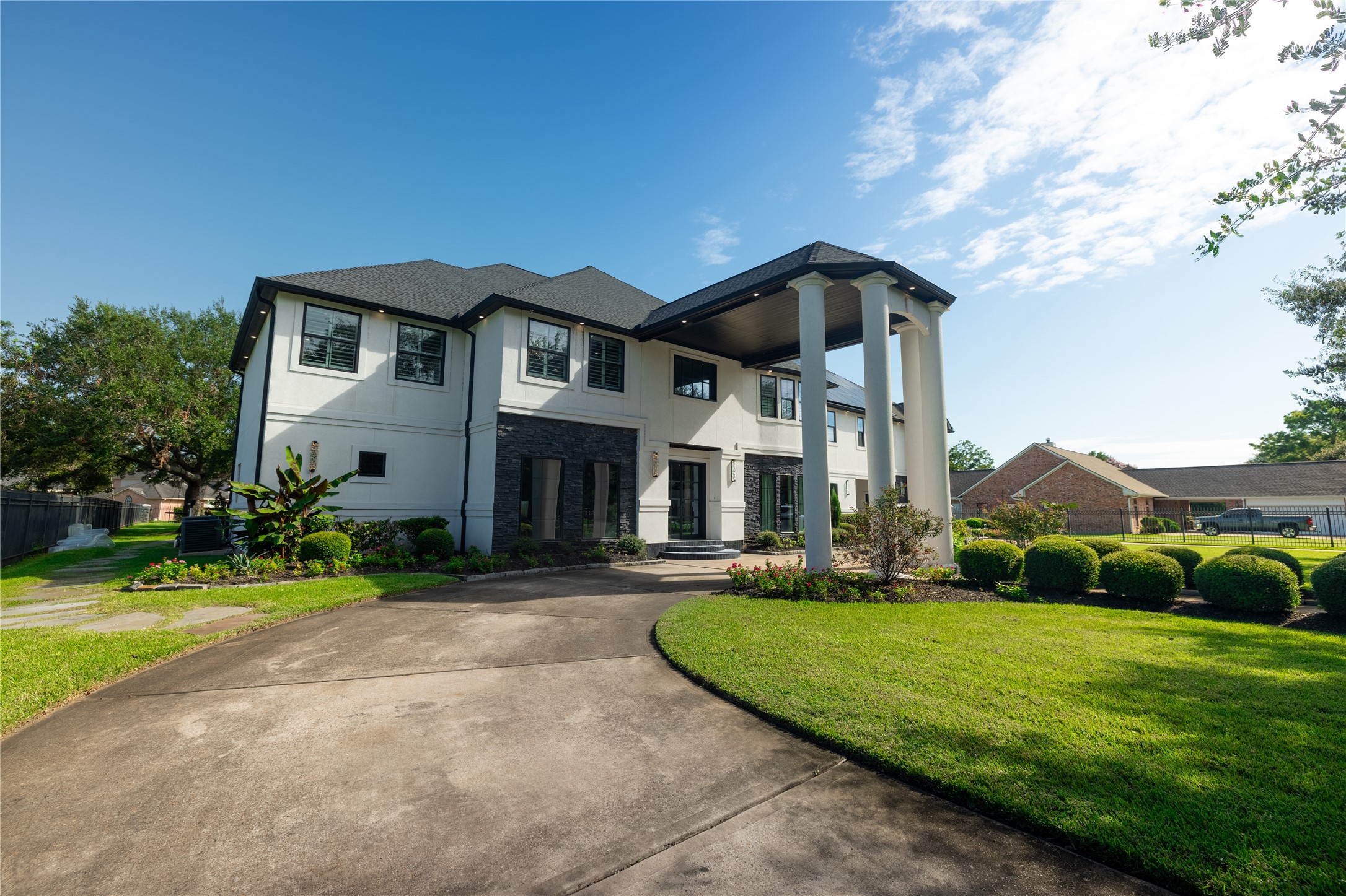 4002 Silver Ridge Boulevard Missouri City, TX 77459 - Photo 3 of 50 This is a spacious two-story home with a grand entrance featuring tall columns. The exterior is a combination of white and dark accents, complemented by a well-maintained lawn and a circular driveway.