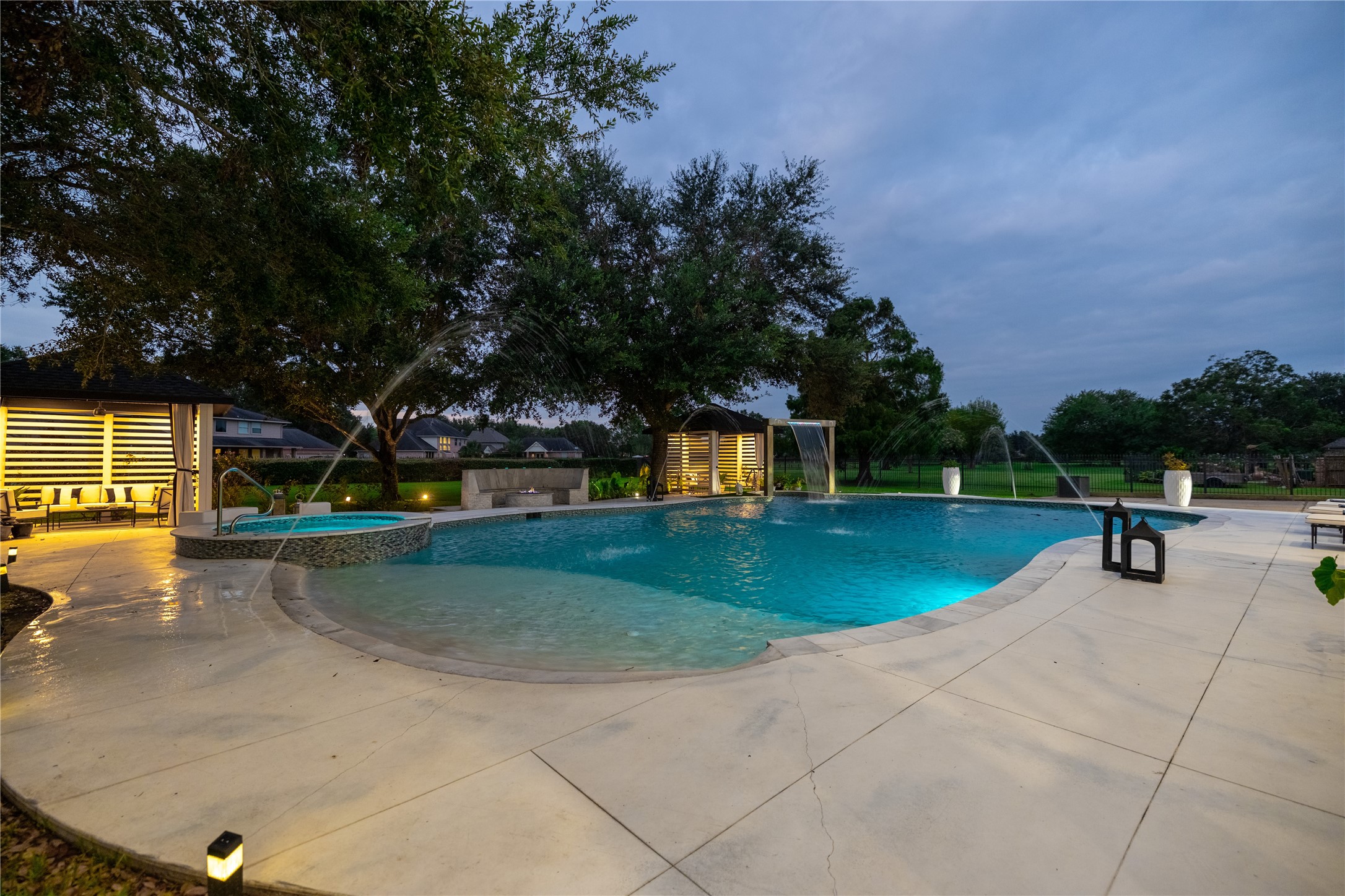 4002 Silver Ridge Boulevard Missouri City, TX 77459 - Photo 38 of 50 This is a spacious backyard featuring an inviting swimming pool with fountains, ample patio space for entertaining, and a cozy poolside cabana, all set against a backdrop of mature trees and a well-maintained lawn.
