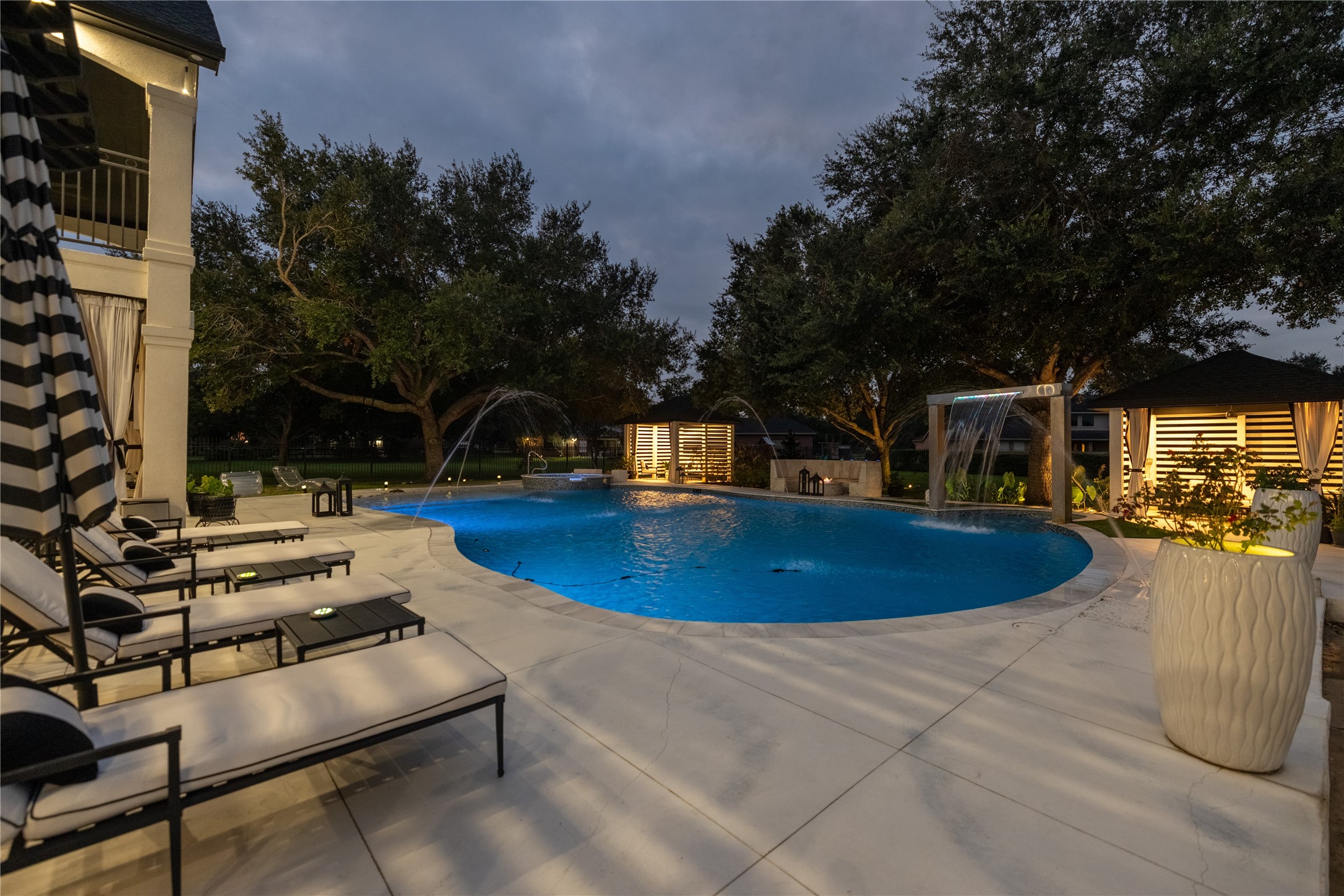 4002 Silver Ridge Boulevard Missouri City, TX 77459 - Photo 43 of 50 Luxurious backyard with an elegant pool, complete with lounge chairs and ambient lighting, offering a perfect oasis for relaxation and entertainment.