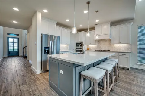 a kitchen with stainless steel appliances granite countertop a table chairs refrigerator and microwave