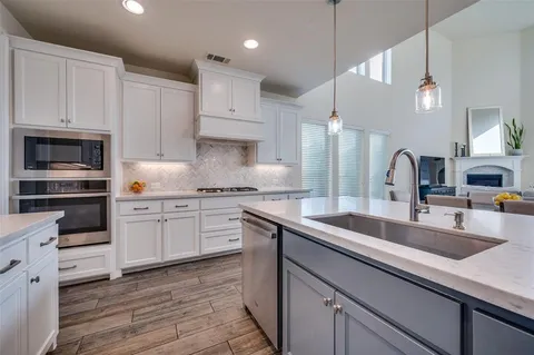a kitchen with kitchen island granite countertop a sink a counter space appliances and cabinets