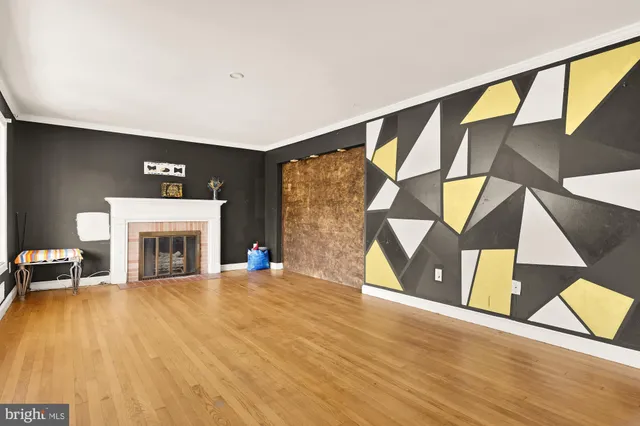 a view of an empty room with wooden floor and a fireplace
