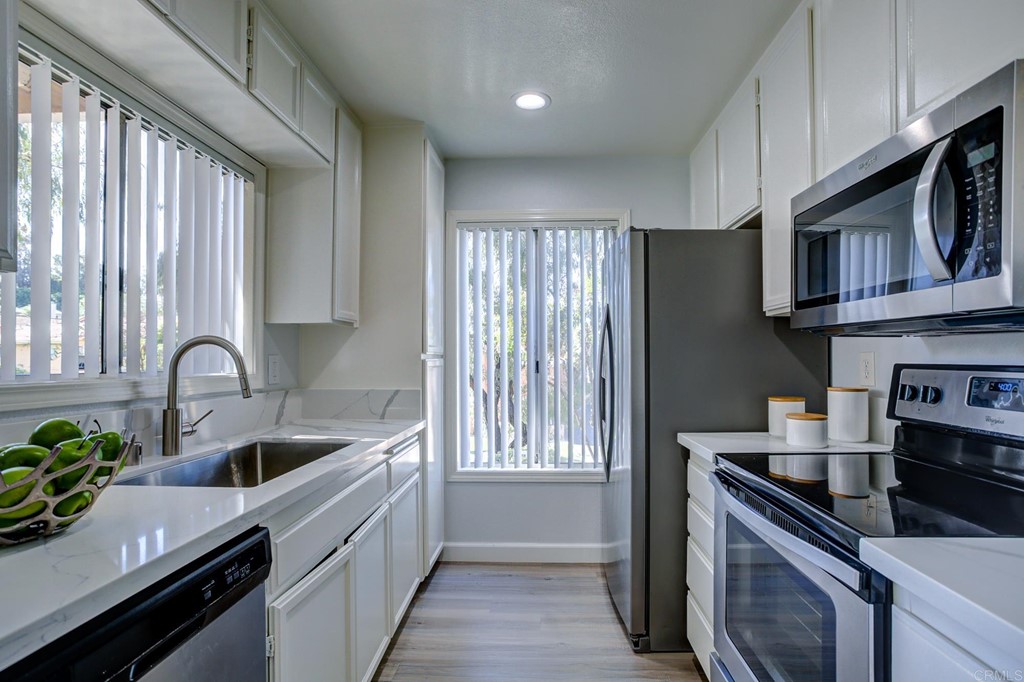 237 Diamond Way, Unit 102 Vista, CA 92083 - Photo 1 of 1 a kitchen with kitchen island granite countertop a sink stainless steel appliances and cabinets