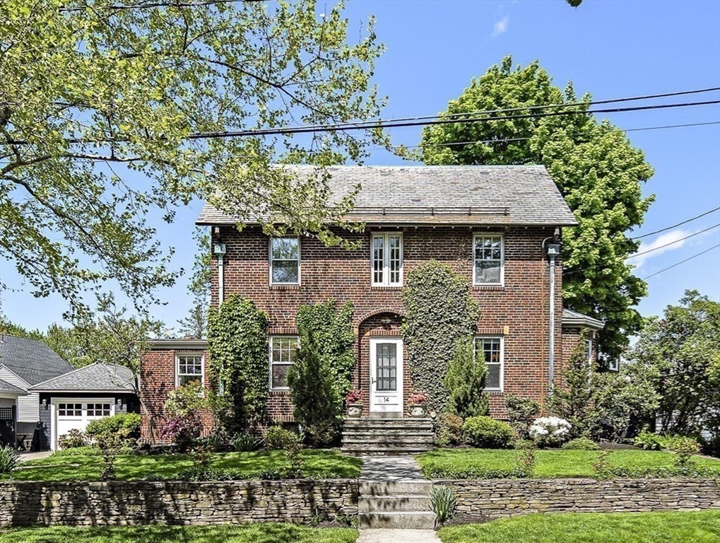 a view of a brick house with a plants and large trees