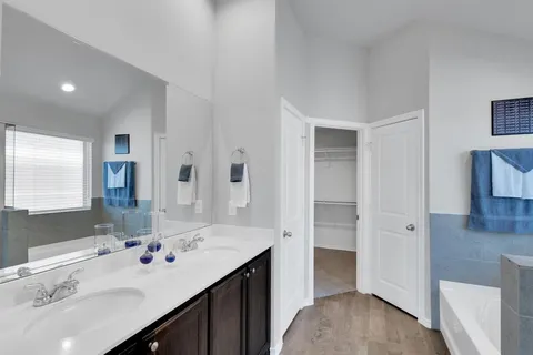 a bathroom with a sink double vanity granite tub shower and a mirror