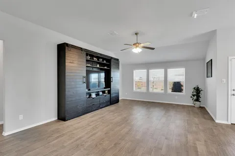 a view of an empty room with a window and wooden floor