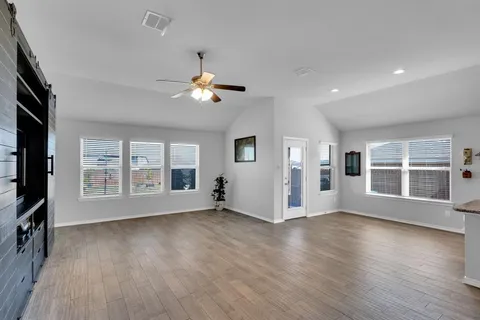 a view of an empty room with a window and wooden floor