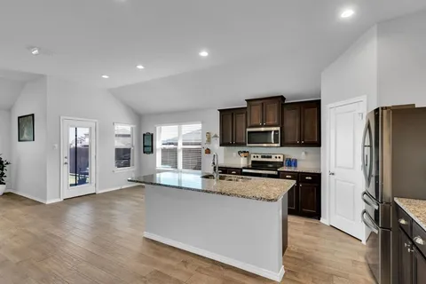 a kitchen with stainless steel appliances granite countertop a refrigerator a stove top oven a sink and dishwasher