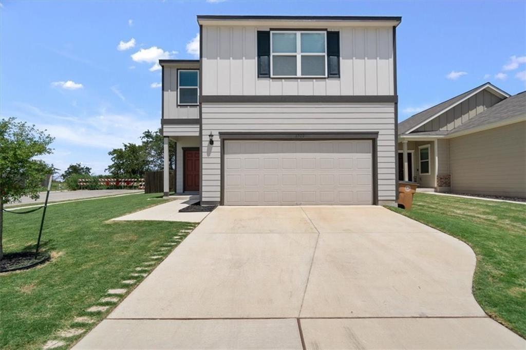 View of front of home with an attached garage, a front yard, board and batten siding, and concrete driveway