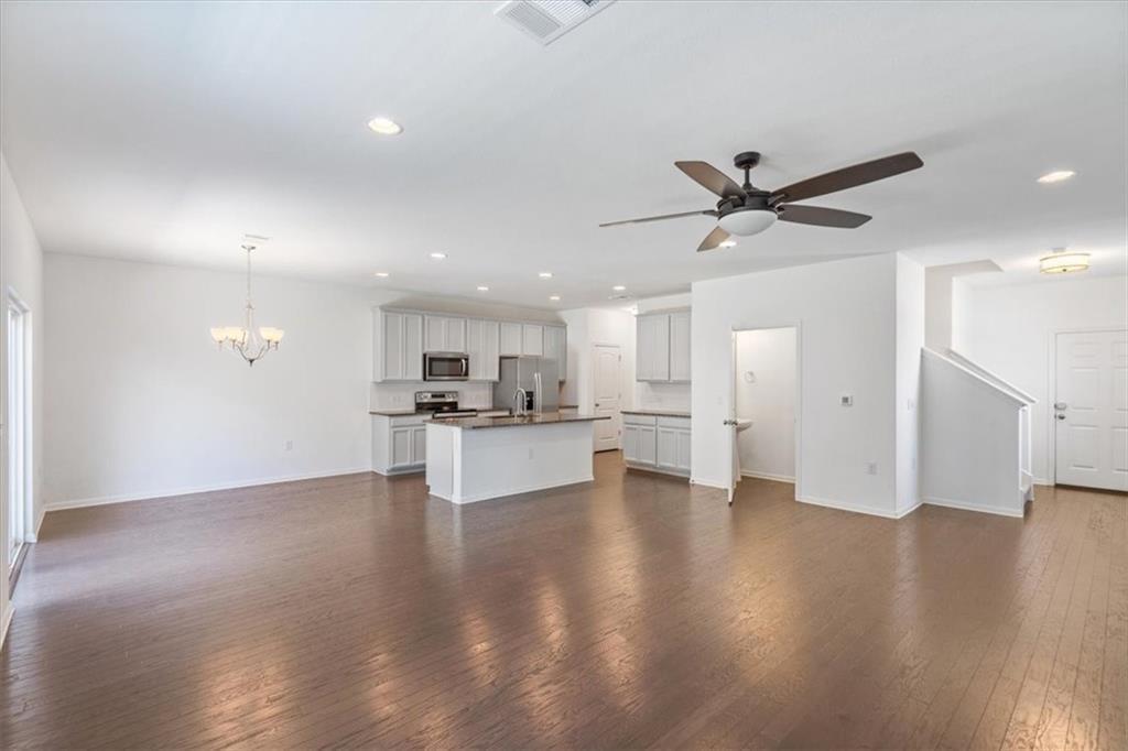 6500 Routenburn Street Austin, TX 78754 - Photo 13 of 38 Unfurnished living room with dark wood-style floors, a ceiling fan, and a chandelier