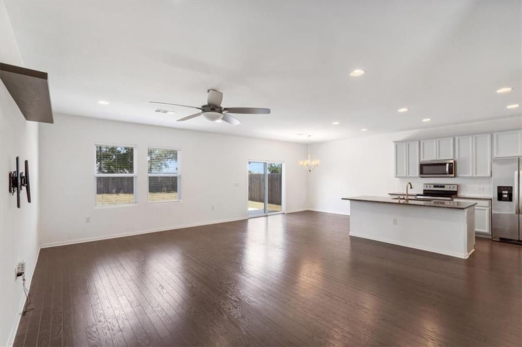 6500 Routenburn Street Austin, TX 78754 - Photo 14 of 38 Unfurnished living room with dark wood-type flooring, a chandelier, and a ceiling fan
