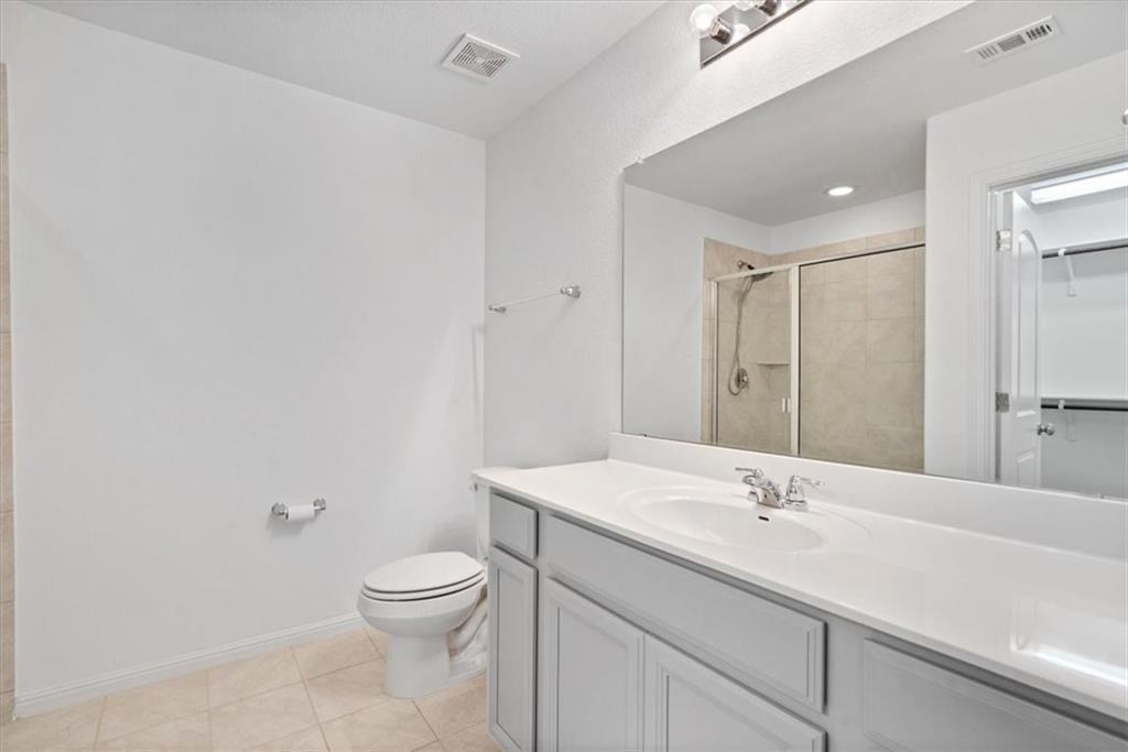 6500 Routenburn Street Austin, TX 78754 - Photo 22 of 38 Bathroom featuring vanity, a stall shower, light tile patterned floors, and a walk in closet