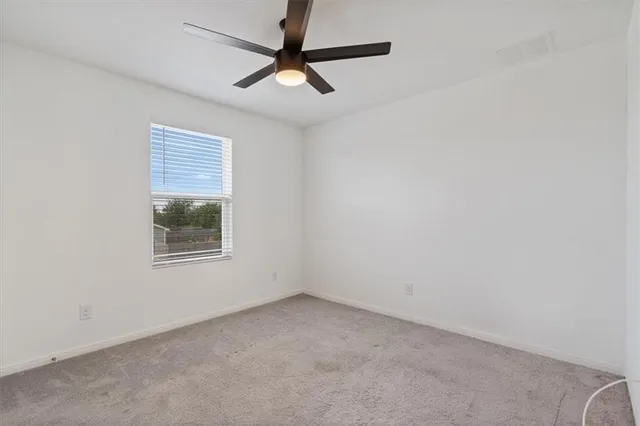 an empty room with a ceiling fan and windows