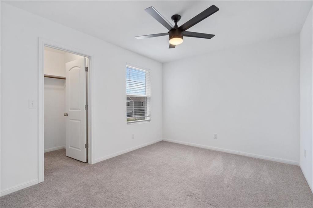 6500 Routenburn Street Austin, TX 78754 - Photo 30 of 38 Unfurnished bedroom featuring light carpet, a walk in closet, and a ceiling fan
