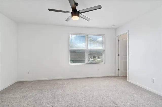 an empty room with a window and a ceiling fan