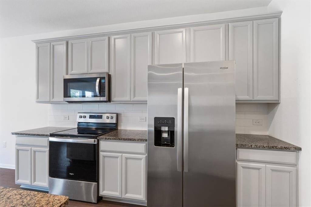 6500 Routenburn Street Austin, TX 78754 - Photo 8 of 38 Kitchen with stainless steel appliances, dark stone countertops, tasteful backsplash, and dark wood finished floors