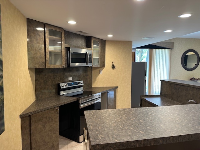 21839 Riviera Court, Unit G Mundelein, IL 60060 - Photo 5 of 17 a kitchen with stainless steel appliances kitchen island granite countertop a stove a sink and a refrigerator