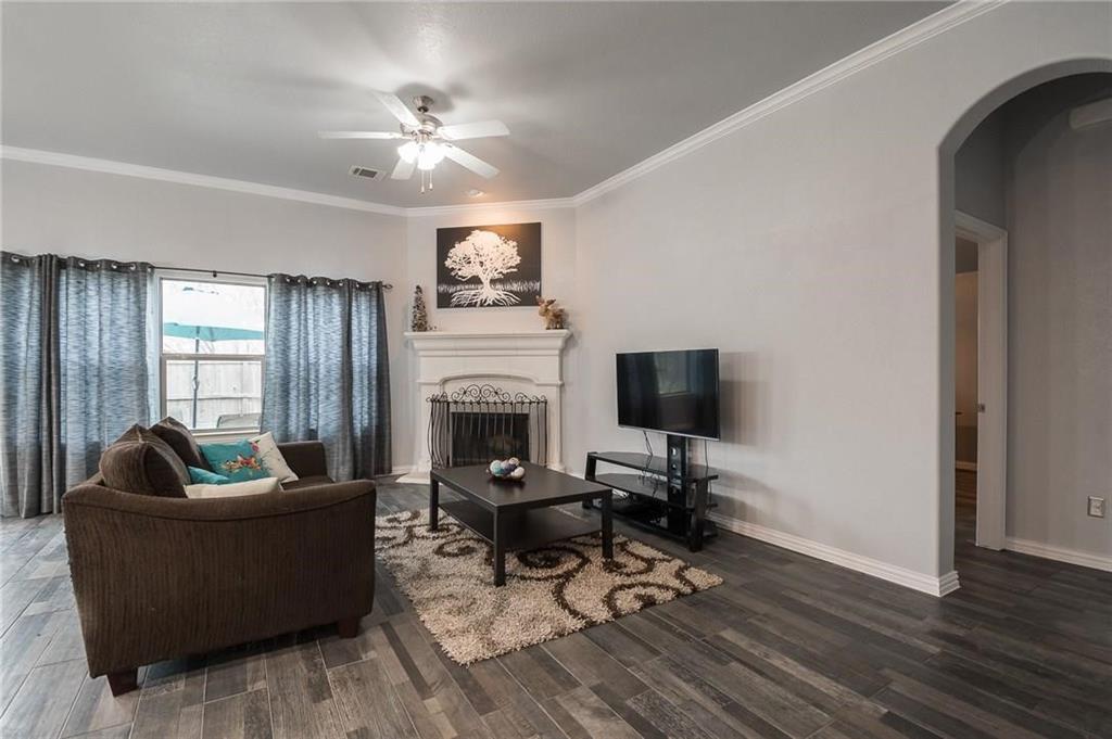 227 Timber Drive Princeton, TX 75407 - Photo 13 of 13 Living room featuring a fireplace, ornamental molding, arched walkways, dark wood-type flooring, and ceiling fan