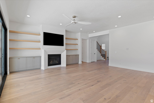 1192 East Corral Way Washington, UT 84780 - Photo 40 of 81 Spacious living area featuring light wood-finish flooring, a recessed fireplace with a white mantel, and built-in cabinetry with light wood shelving