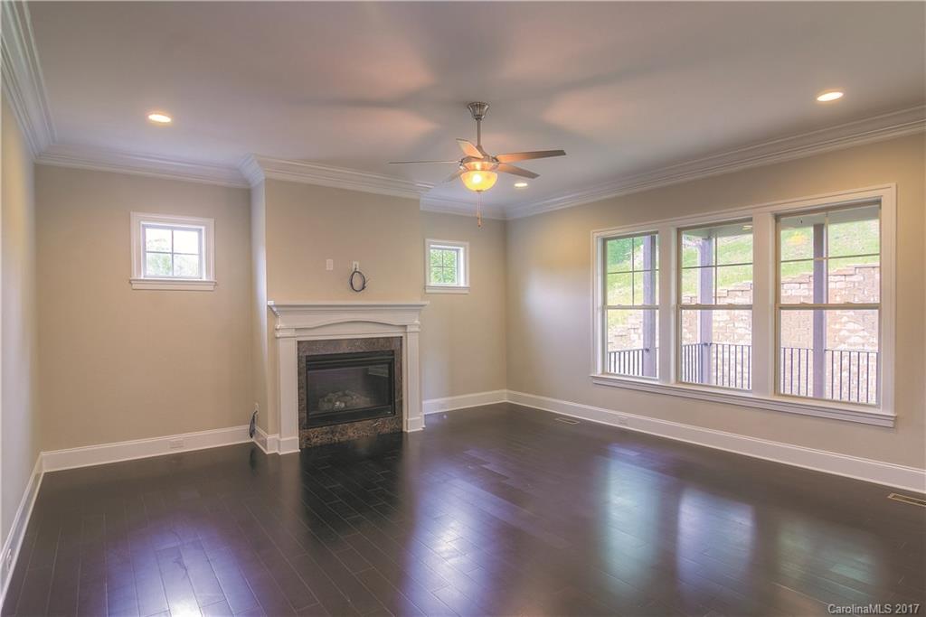 160 Forsythia Lane, Unit 739 Tega Cay, SC 29708 - Photo 4 of 24 an empty room with wooden floor fireplace and windows