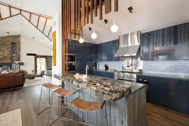 a kitchen with granite countertop a stove a sink dishwasher a dining table and chairs with wooden floor