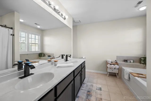 a bathroom with a double vanity sink a mirror and a bathtub