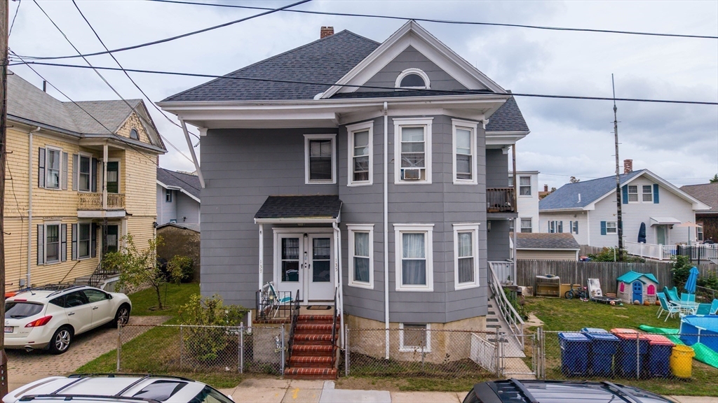 135-137 Query Street New Bedford, MA 02745 - Photo 15 of 17 a front view of a residential apartment building with a yard