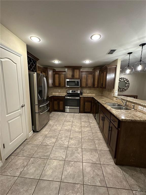 4608 Robin Avenue McAllen, TX 78504 - Photo 2 of 12 Kitchen featuring stainless steel appliances, wood cabinetry, granite countertops, and tile flooring