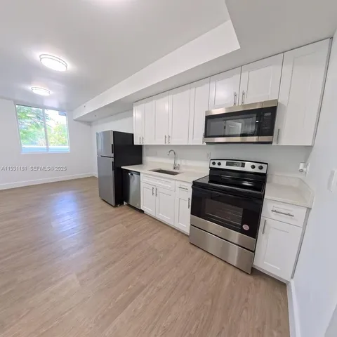 a kitchen with granite countertop a refrigerator and a stove top oven
