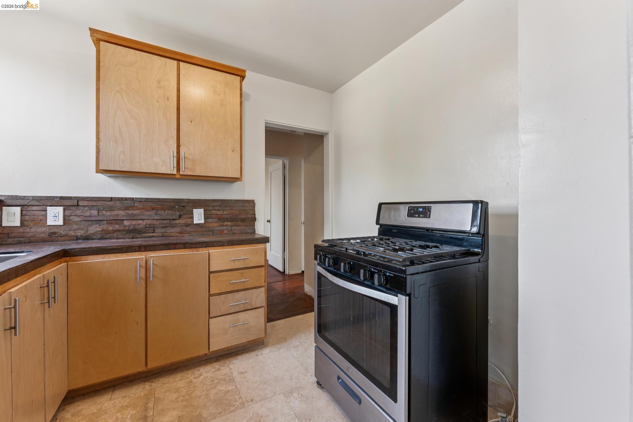 2879 Rheem Avenue Richmond, CA 94804 - Photo 21 of 45 Kitchen featuring light wood cabinetry with brushed nickel hardware, stone-look countertops, and a stacked stone-look backsplash