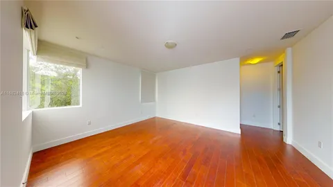 a view of an empty room with window and wooden floor