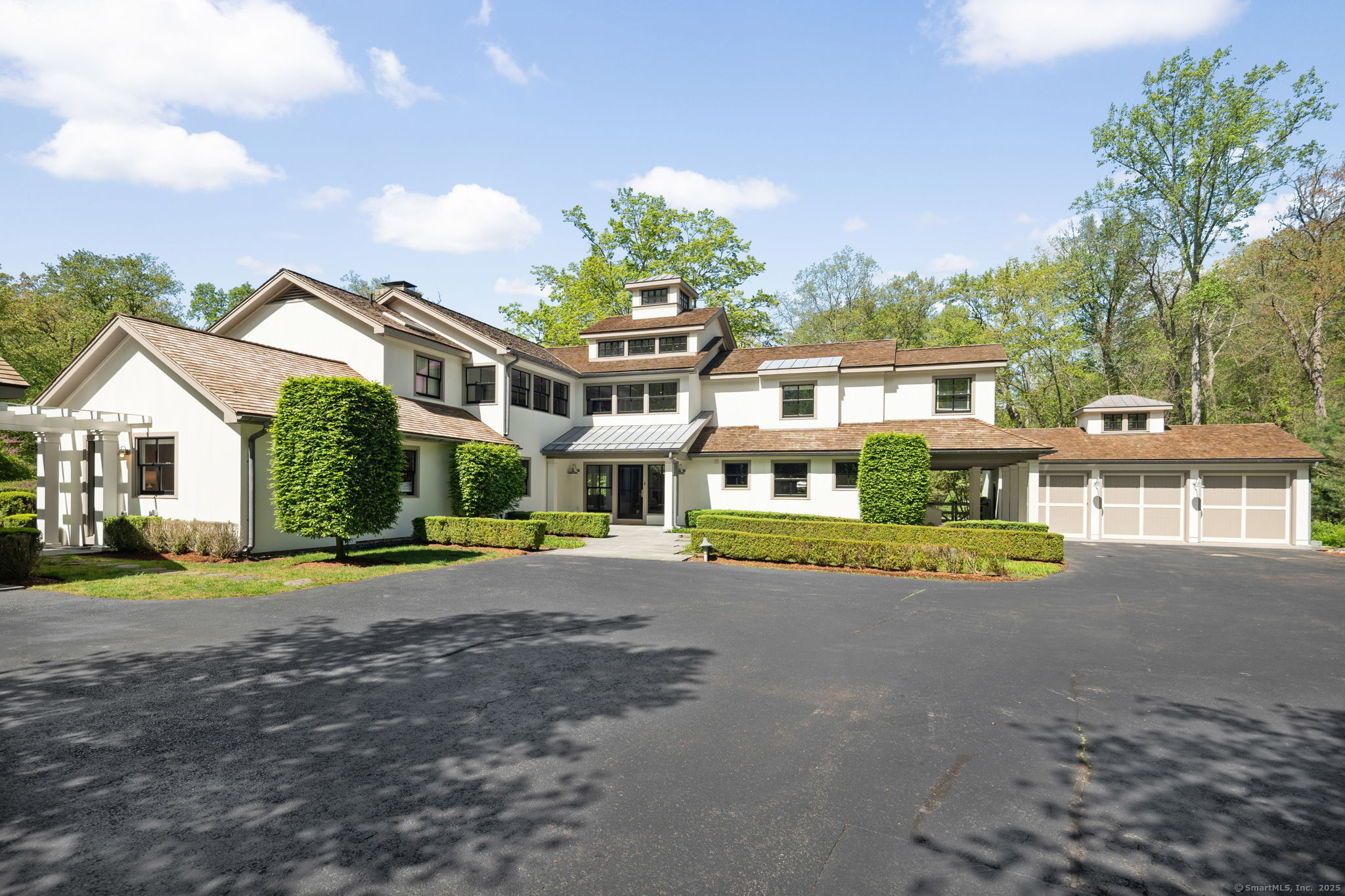 a view of a white house next to a yard with large trees