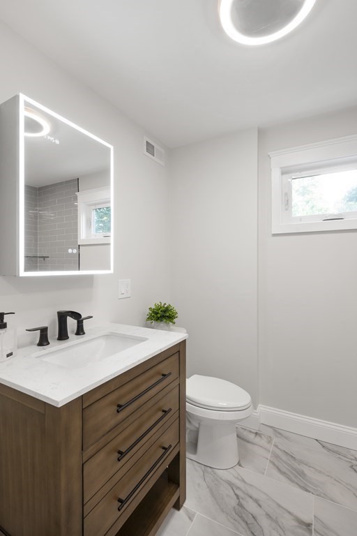 8 Lovell Road Watertown, MA 02472 - Photo 31 of 42 a bathroom with a granite countertop sink a toilet and a mirror