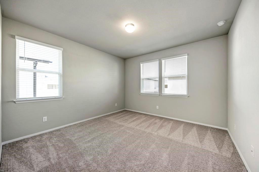 1209 Goforth Road Kyle, TX 78640 - Photo 15 of 32 An airy bedroom with fresh carpet and ample natural light from multiple windows.