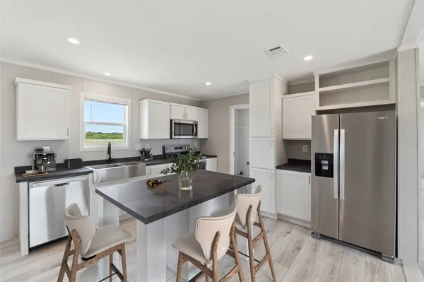 a kitchen with a refrigerator a stove a sink a dining table and chairs