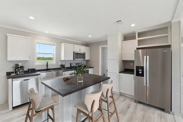 a kitchen with a refrigerator a stove a sink a dining table and chairs