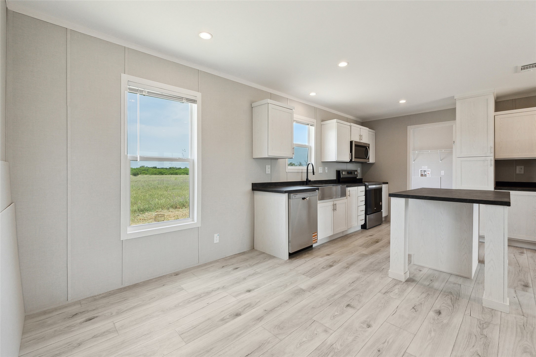 1287 Cr 402 Roads, Unit LOT 17 Flatonia, TX 78941 - Photo 16 of 37 Kitchen with stainless steel appliances, a sink, dark countertops, light wood-style flooring, and white cabinetry