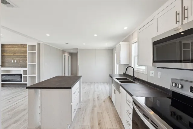 a kitchen with stainless steel appliances a stove a sink a microwave a refrigerator and cabinets