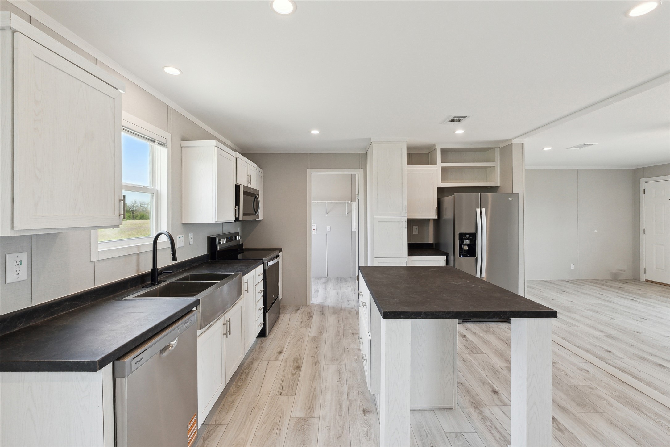 1287 Cr 402 Roads, Unit LOT 17 Flatonia, TX 78941 - Photo 23 of 37 Kitchen featuring stainless steel appliances, open shelves, a sink, a kitchen island, and light wood-style flooring