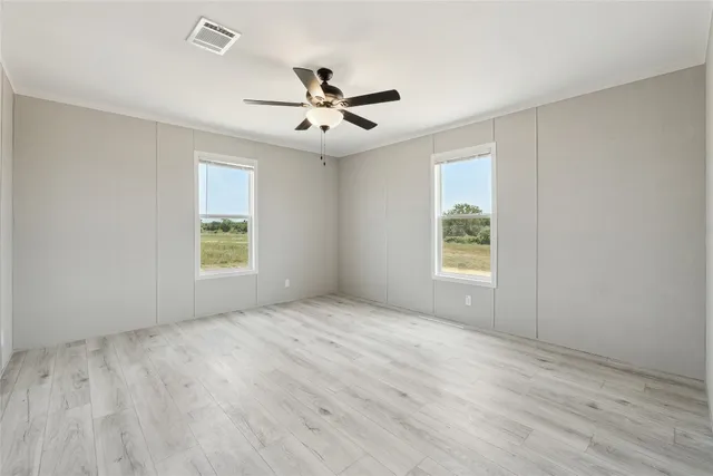 a view of empty room with wooden floor and fan