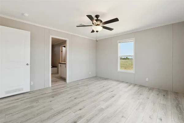 a view of empty room with wooden floor and fan