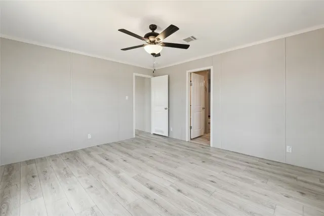 a view of empty room with wooden floor and ceiling fan
