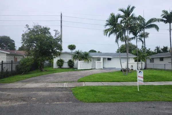 a front view of a house with garden and trees