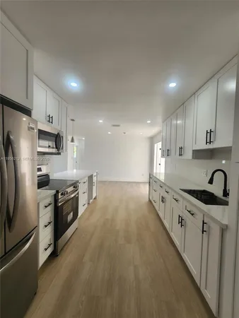a large white kitchen with wooden floors and white cabinets